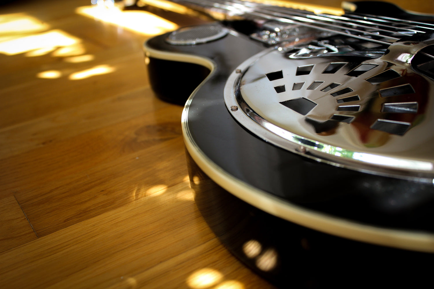 Phillips Design Masterpiece black guitar reflects sunlight onto wooden floor